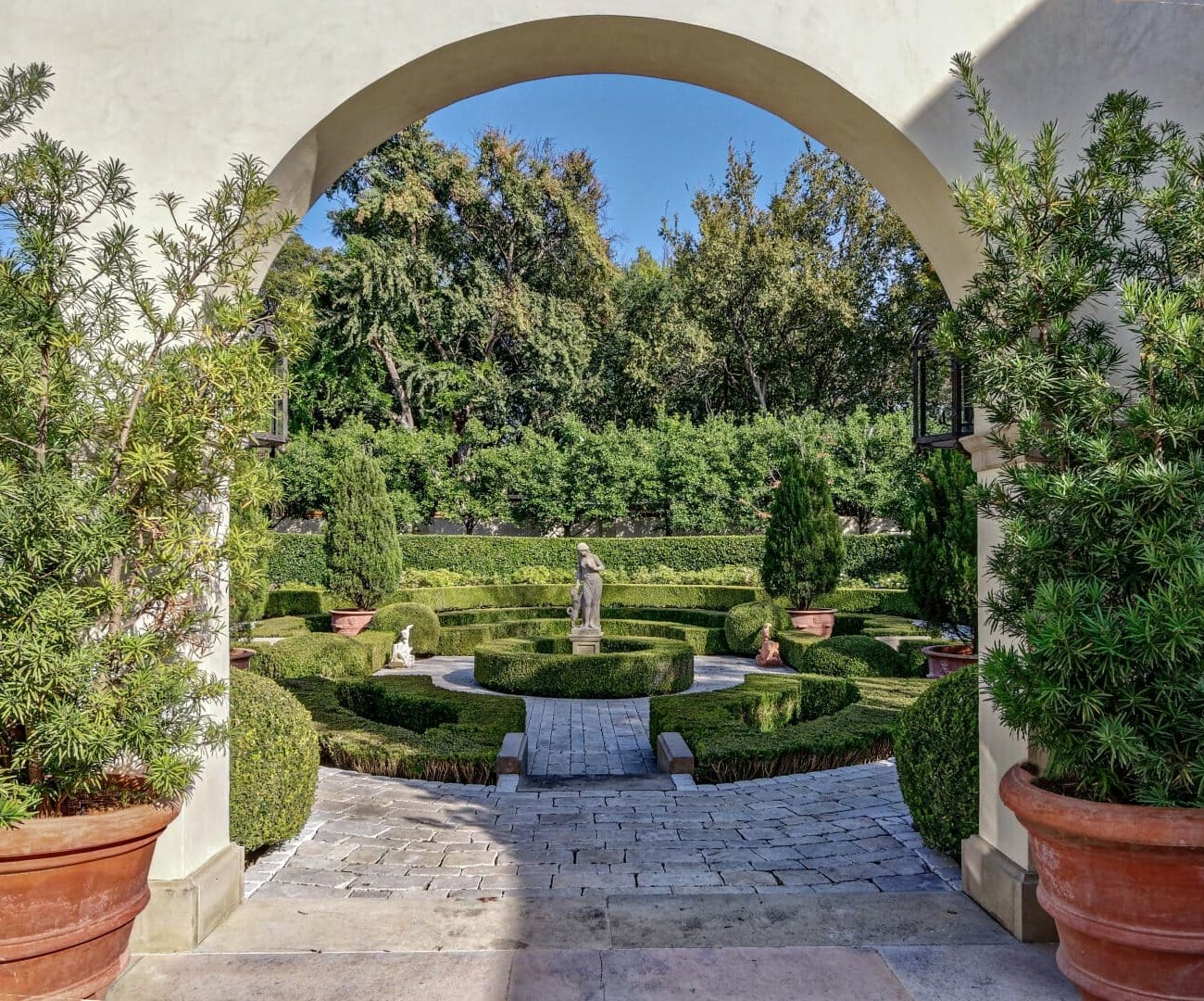a garden with lush landscaping with a stone walkway and a statue